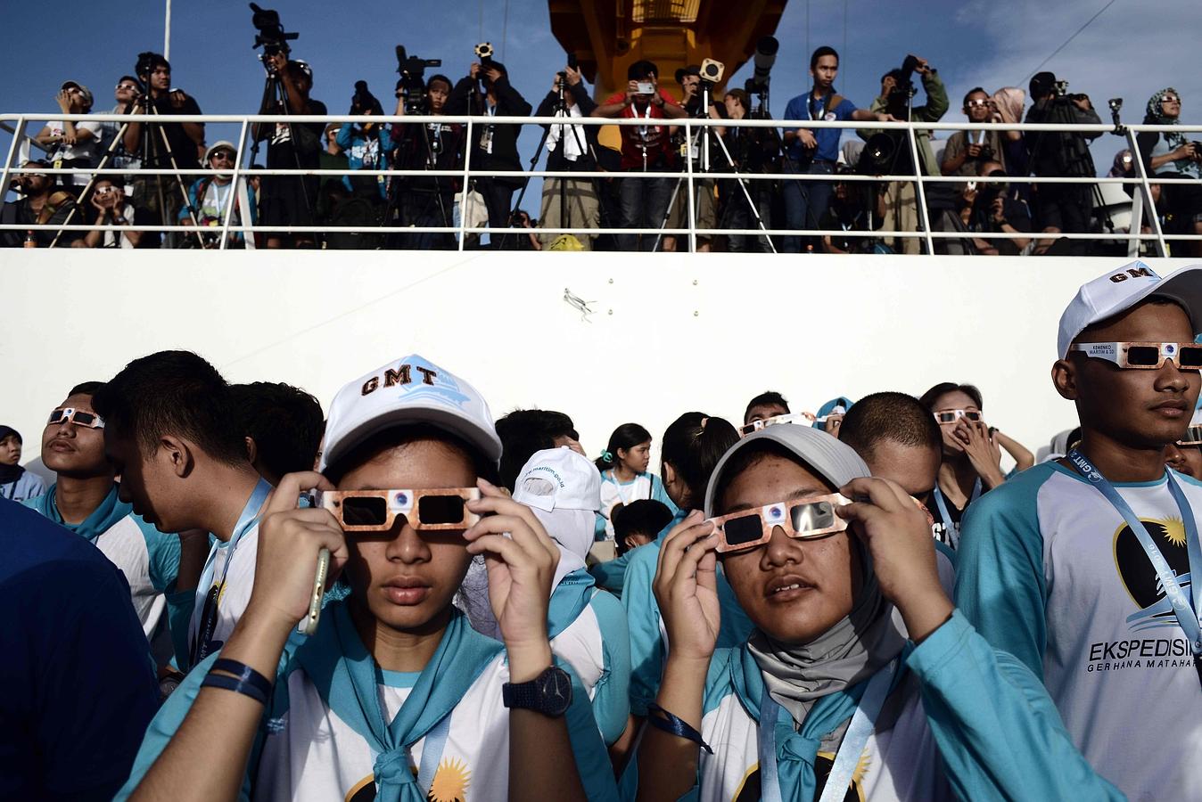 Un grupo de pasajeros de un barco contemplan el eclipse en Indonesia. 