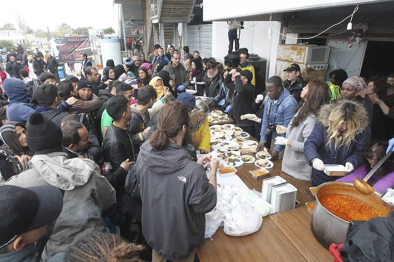 Un grupo de voluntarios reparte ayer comida a refugiados en el antiguo aeropuerto de Elliniko, Grecia. 