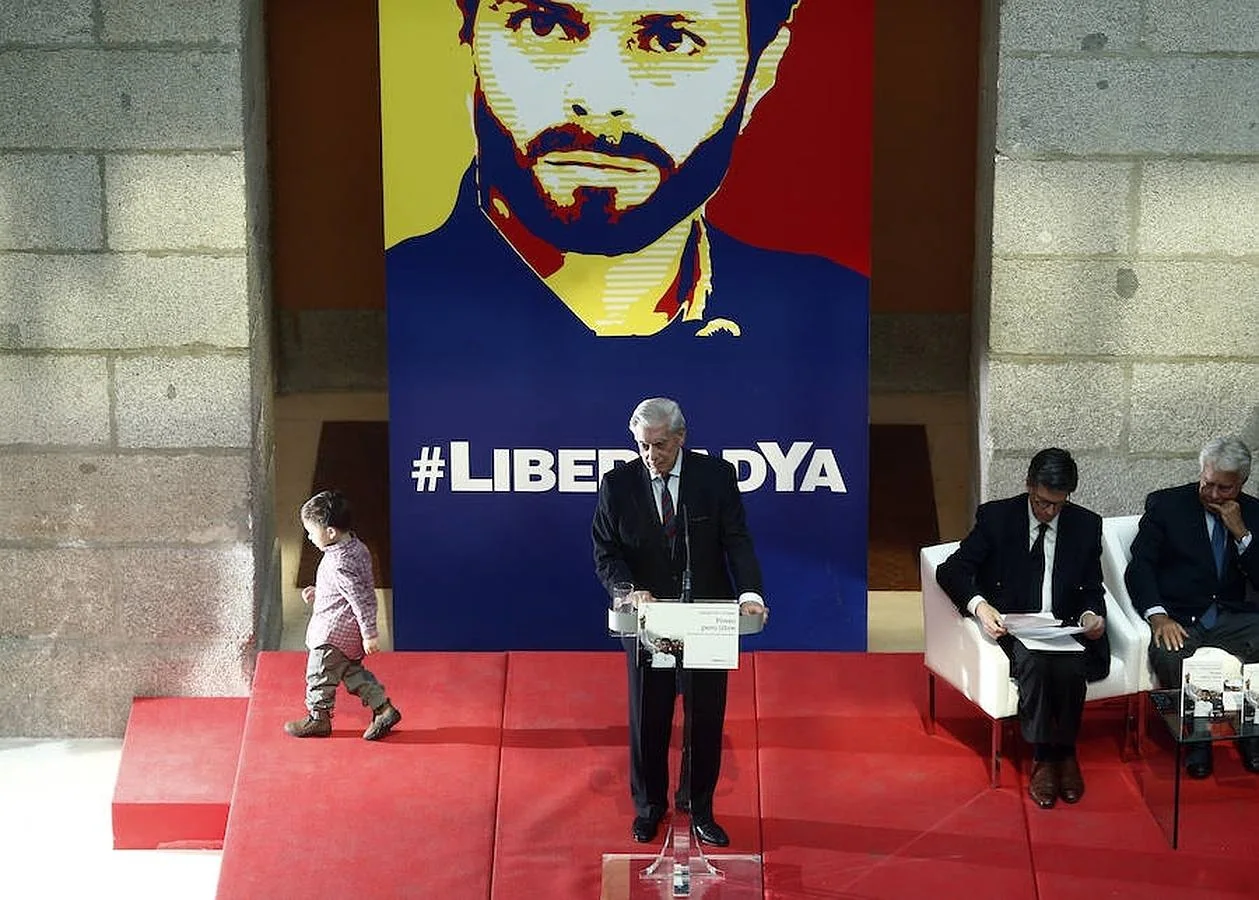 Mario Vargas Llosa pronuncia su discurso mientras por detrás pasa el hijo de Leopoldo López 