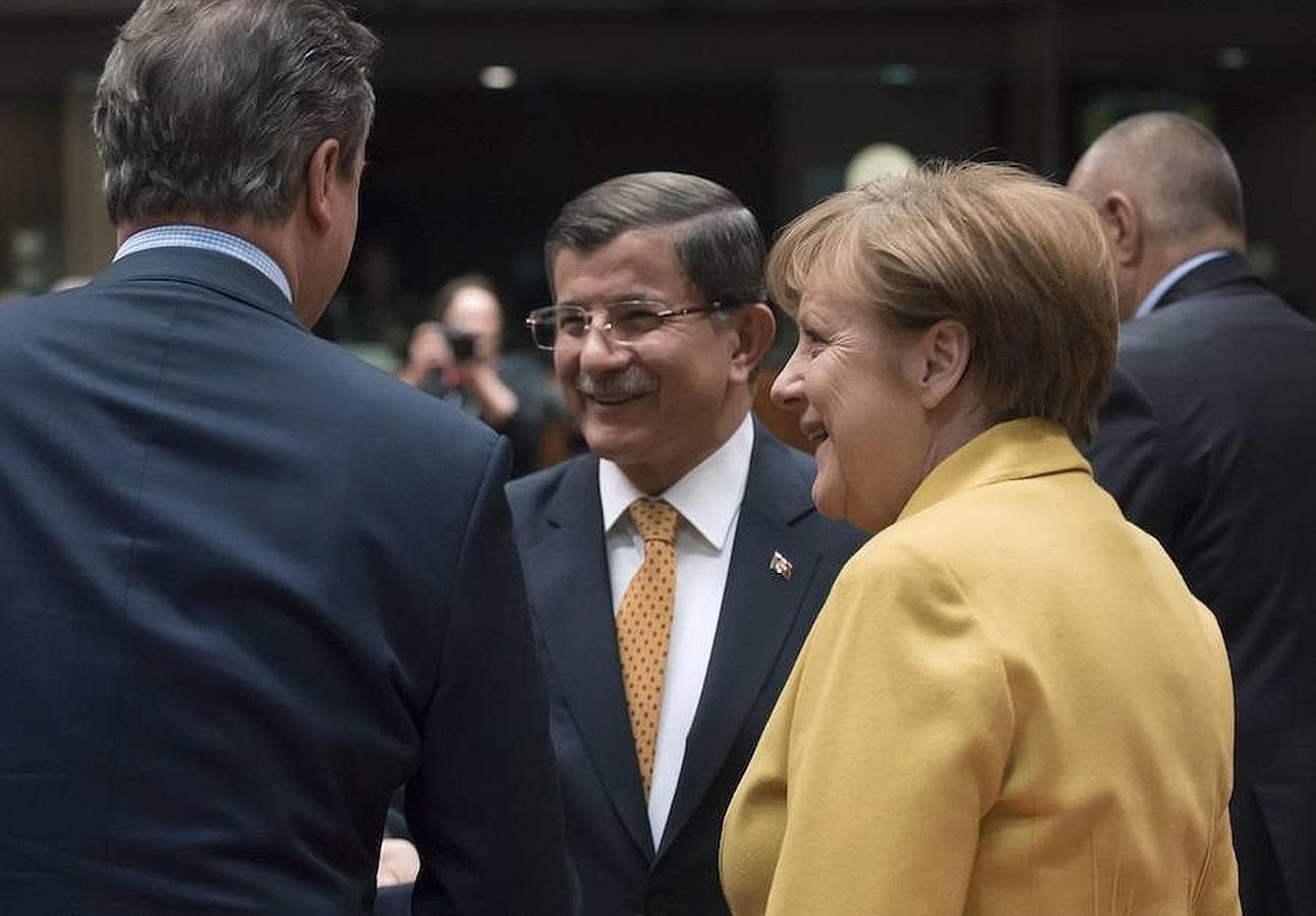 La canciller alemana, Angela Merkel, el primer ministro turco, Ahmet Davutoglu, y el primer ministro británico, David Cameron (de espaldas), durante la cumbre de la UE en Bruselas donde este viernes se llegó a un acuerdo con Turquía sobre los refugiados