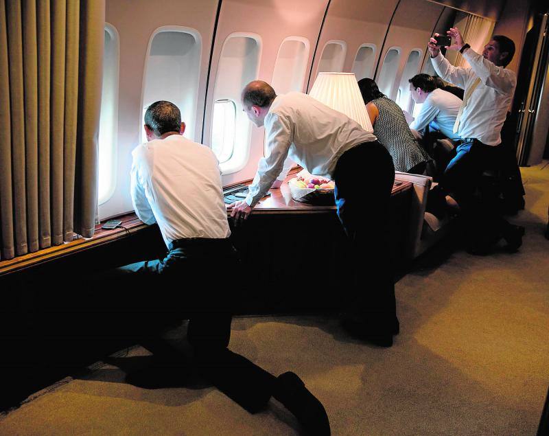 Barack Obama, junto a otros miembros de su comitiva, mirando por la ventana del avión presidencial en la aproximación final a la Habana. 