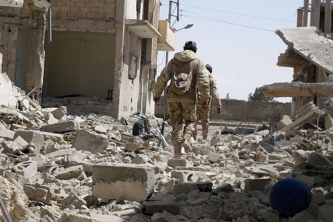 Las tropas gubernamentales caminan sobre la montaña de escombros que han dejado los combates. 