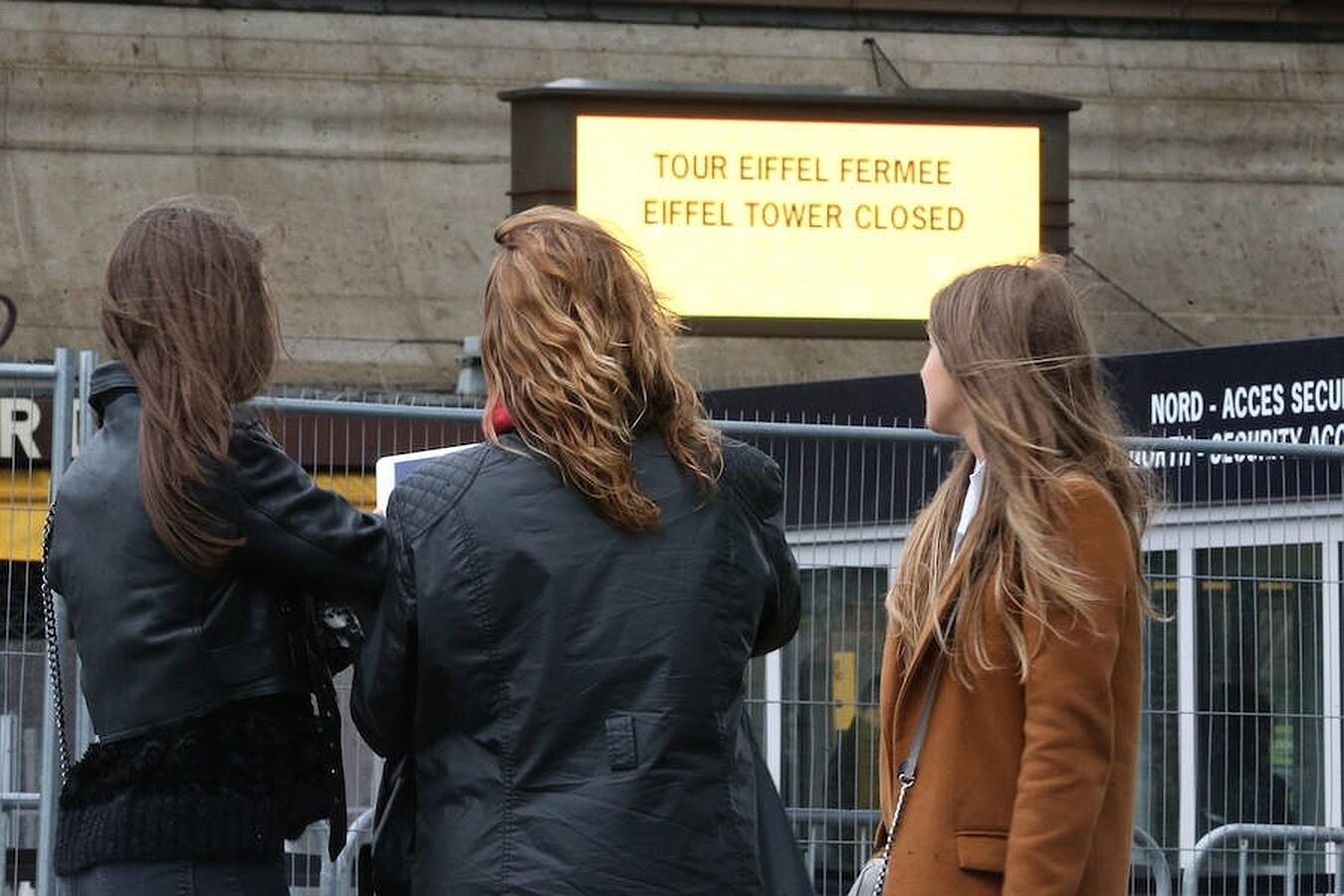 Un grupo de turistas leen en los paneles de información que la Torre Eiffel permanecerá hoy cerrada, debido a los paros convocados como protesta por la reforma laboral