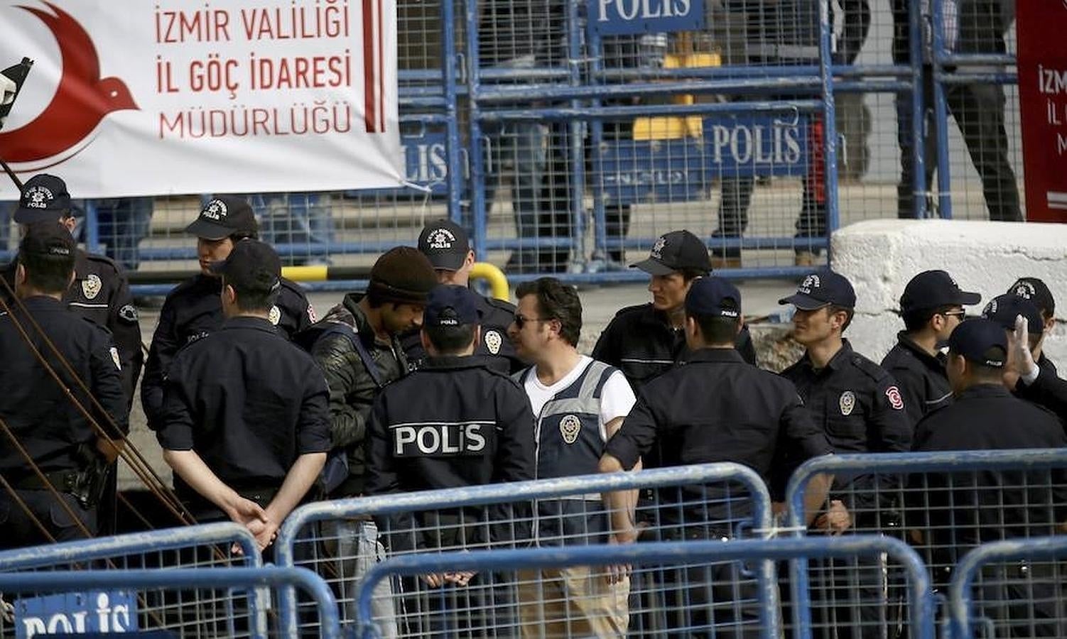 Policías turcos escoltan a los refugiados que fueron deportados desde la isla griega de Lesbos, a su llegada en barco a Izmir, Turquía. 