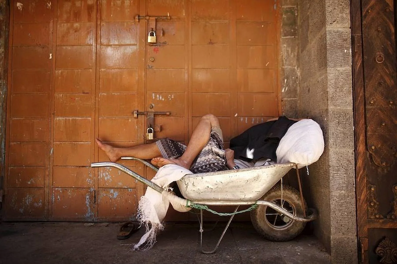 Un hombre duerme sobre una carretilla fuera de un mercado cerrado en el primer día de tregua