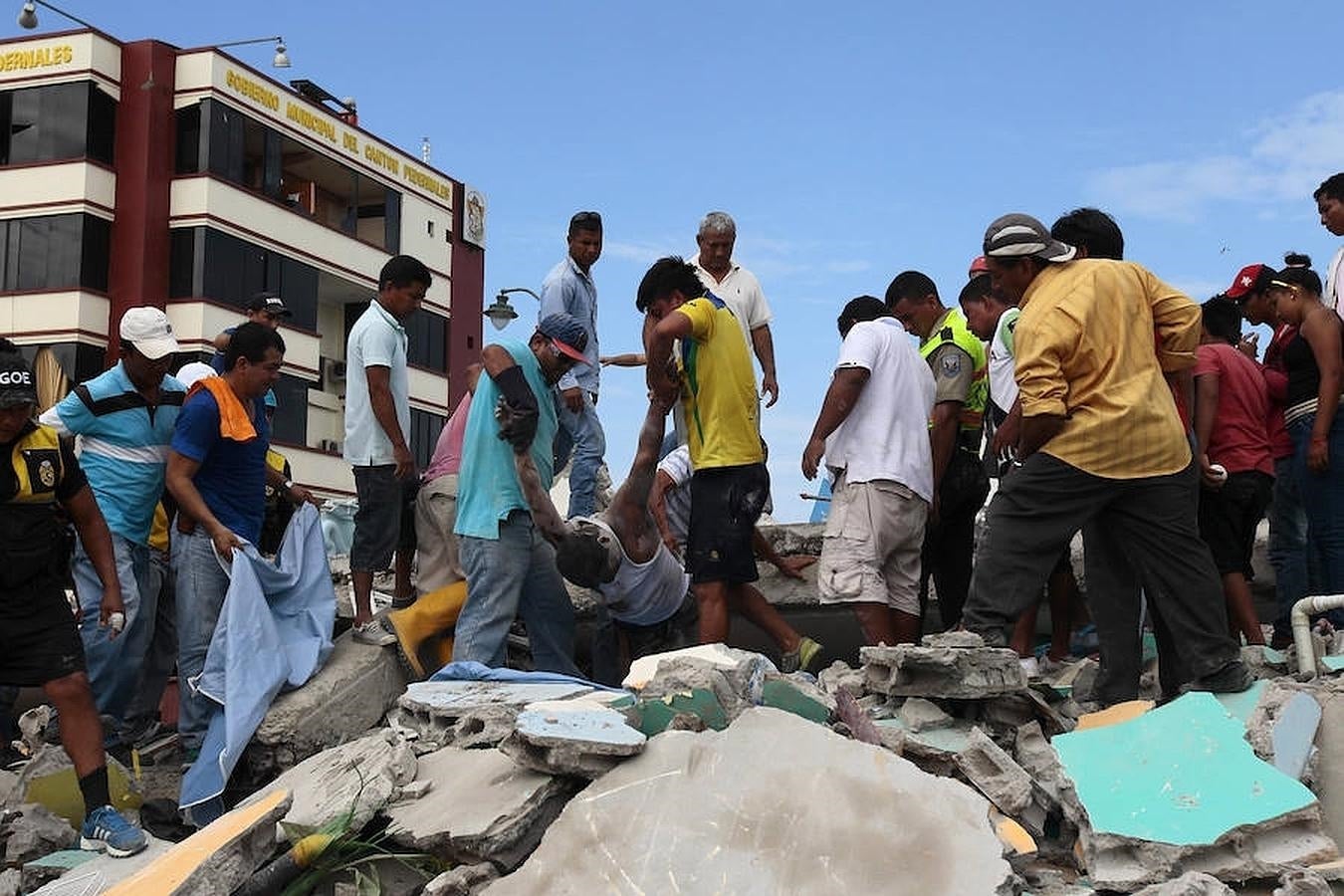 Unos hombres recuperan cuerpos de entre las ruinas del terremoto. 