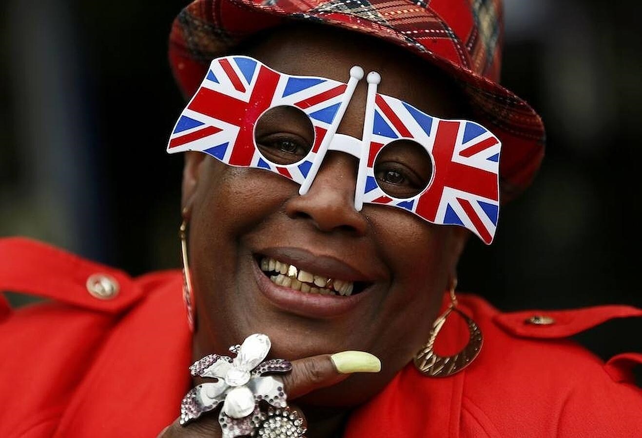 Una mujer posa sonriente con unas gafas con la forma de la bandera británica 