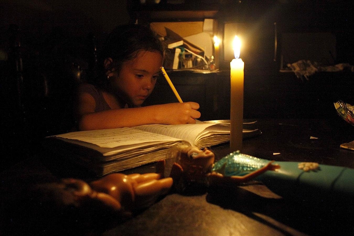Una niña hace los deberes con una vela durante el apagón en San Cristóbal, Venezuela