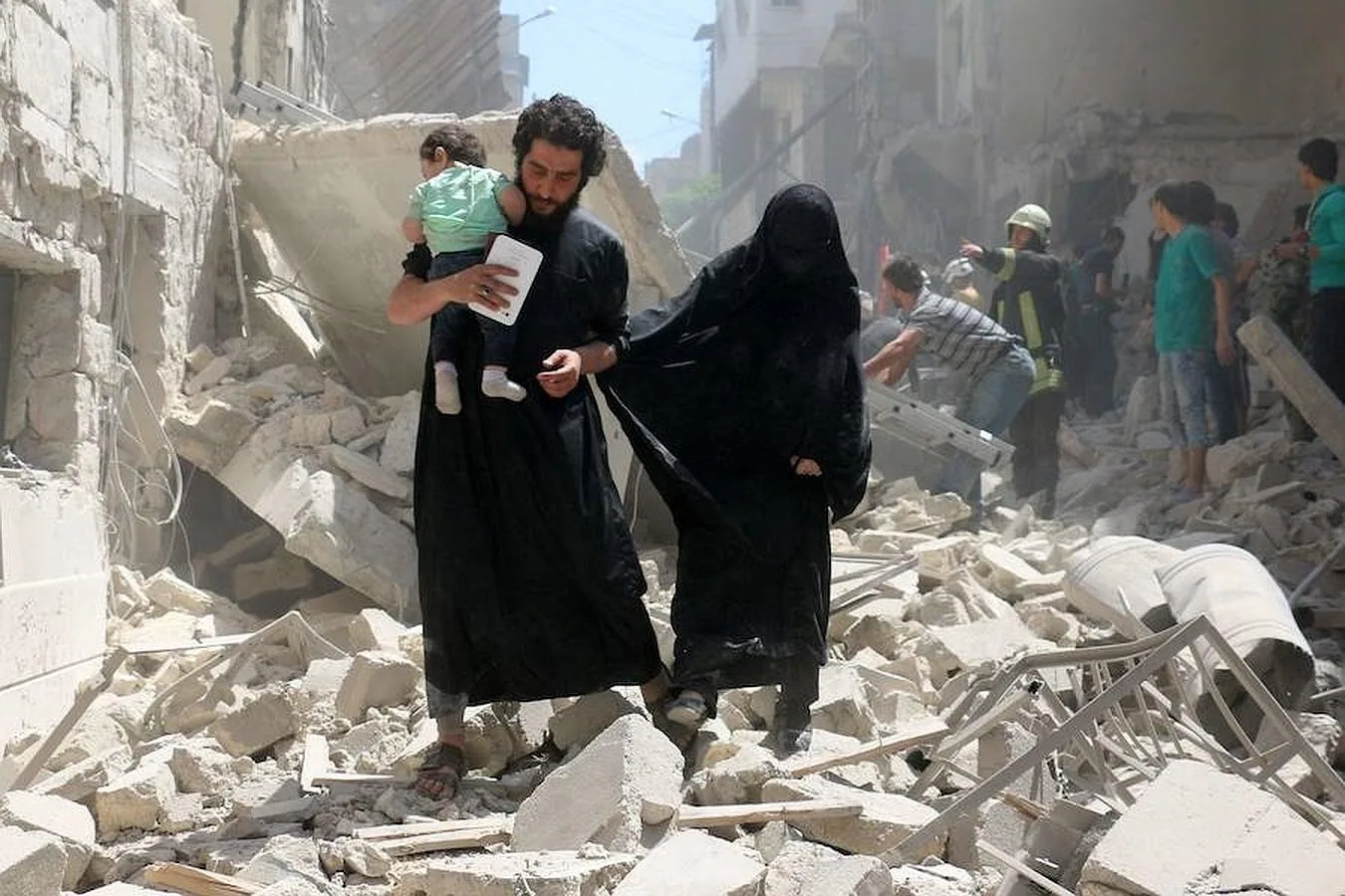 Una familia siria camina en medio de los escombros de edificios destruidos tras el bombardeo