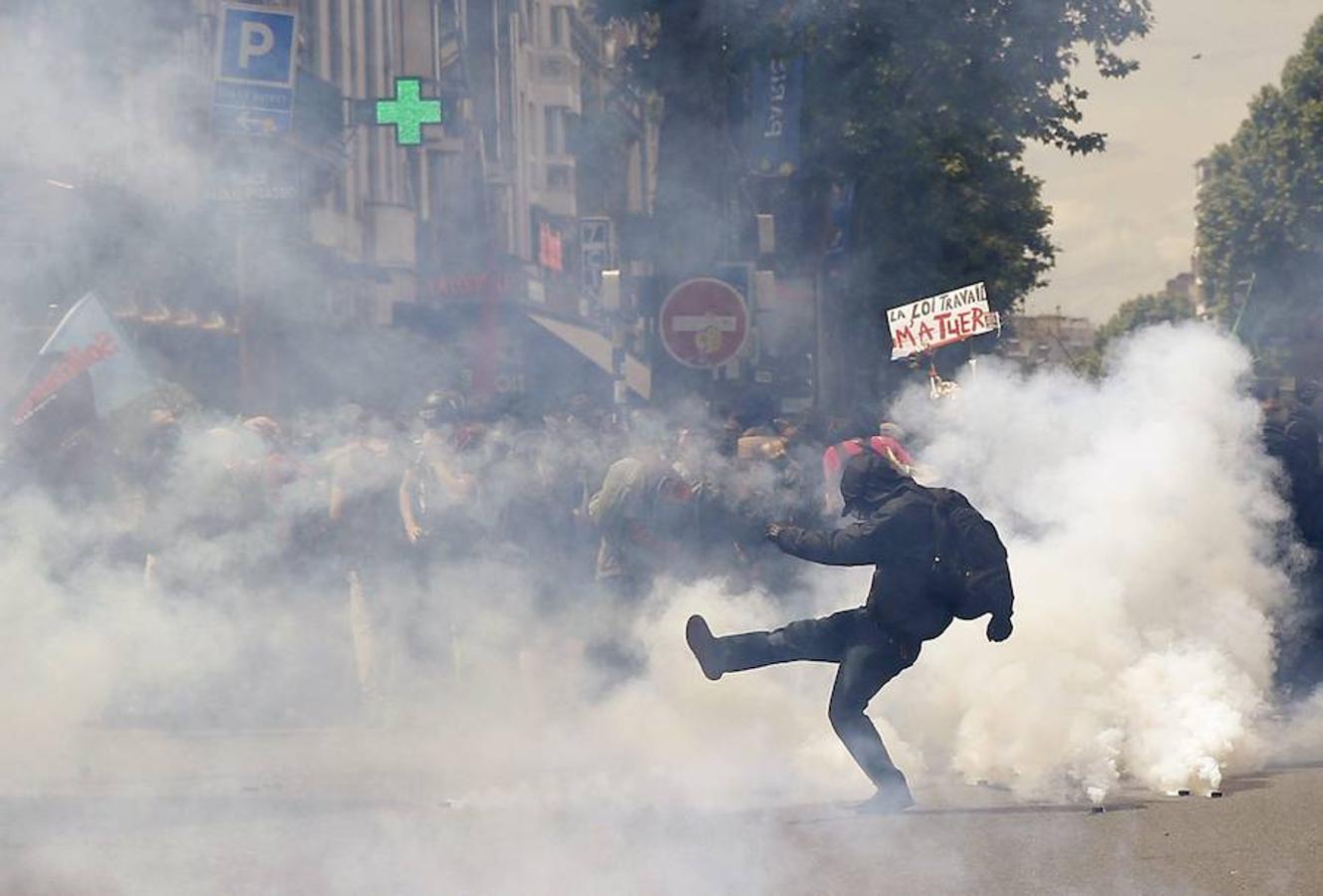 Uno de los manifestantes que se oponen a la reforma laboral del Gobierno pega una patada a un bote de gas lacrimógeno durante los disturbios con la policía en París. 