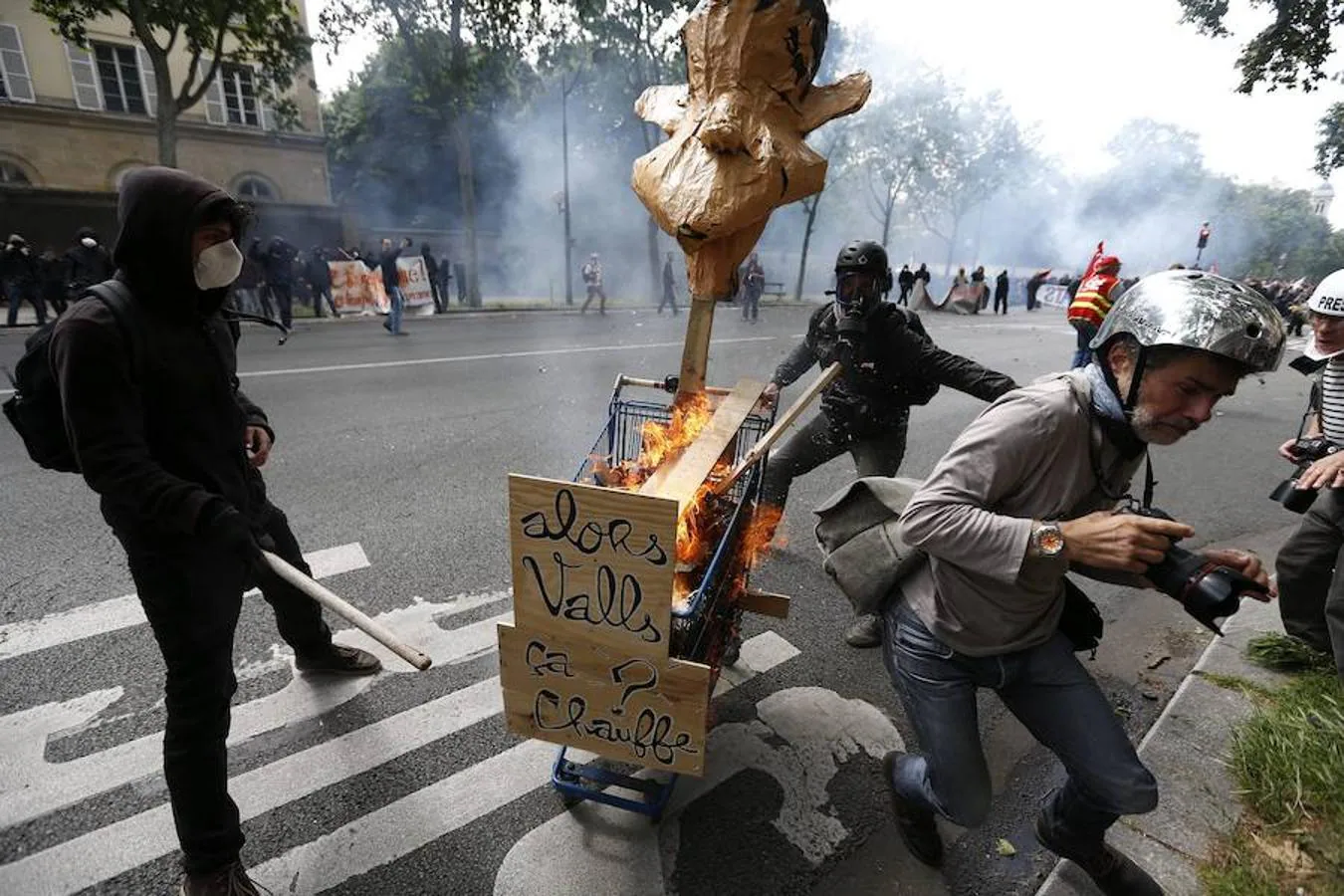 Vista de un carrito ardiendo con carteles que rezan «Ey, Valls ¿hace calor?». 