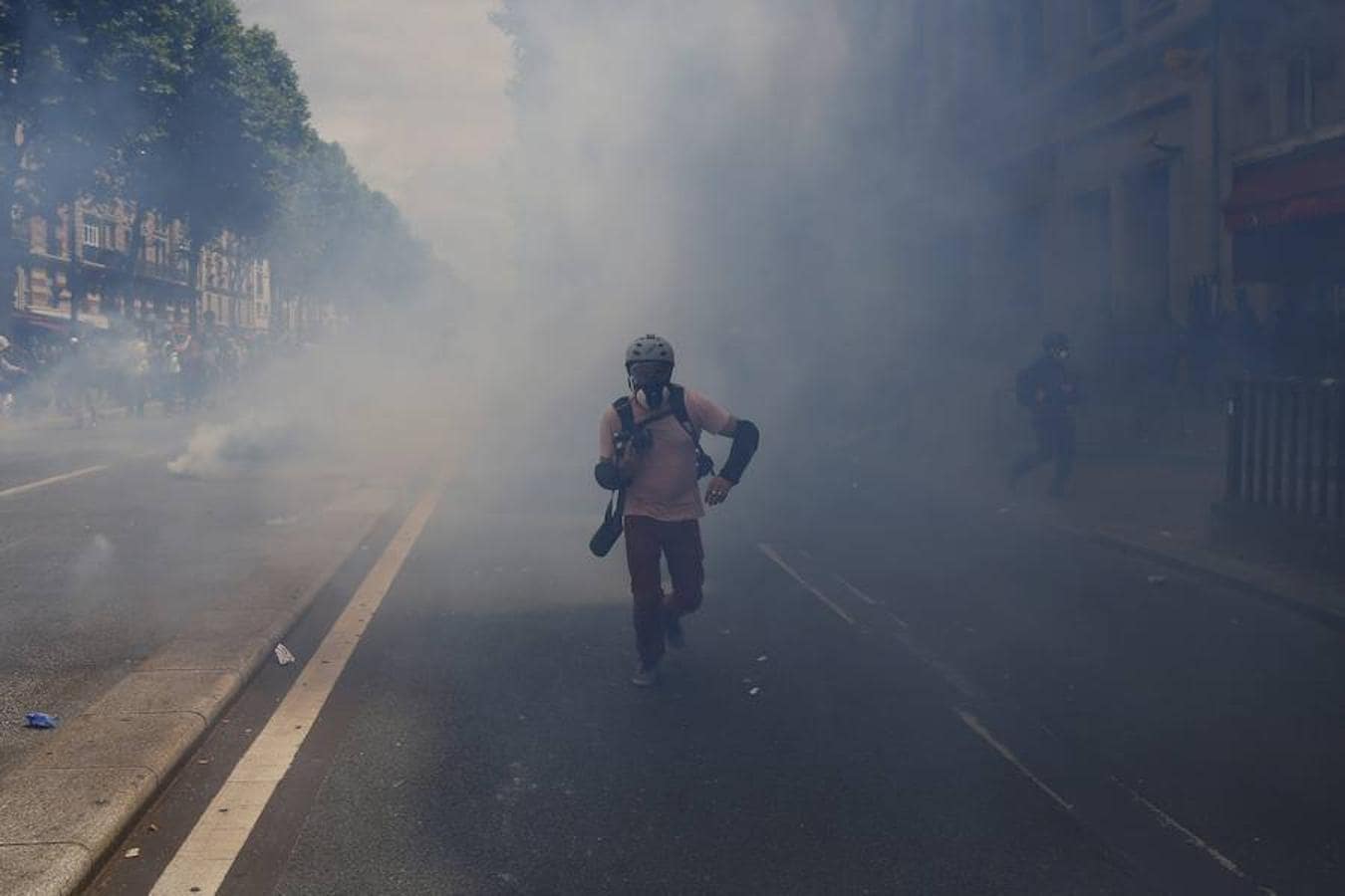Un fotógrafo corre tras el lanzamiento de los gases lacrimógenos durante los disturbios entre la Policía y los manifestantes. 