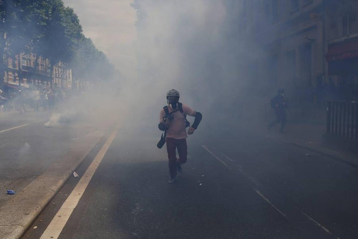 Un fotógrafo corre tras el lanzamiento de los gases lacrimógenos durante los disturbios entre la Policía y los manifestantes. 