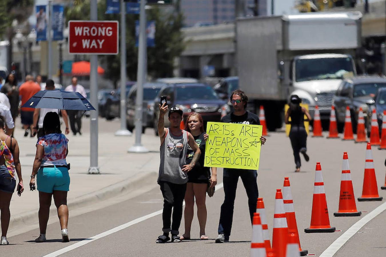 Un hombre, situado en la autopista por donde tiene que pasar Obama, se coloca con un cartel en el que denuncia que los AR-15, el arma utilizada en la matanza del club Pulse, es un «arma de destrucción masiva». 