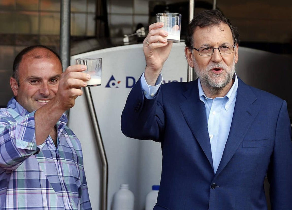 El presidente del Gobierno en funciones, Mariano Rajoy, junto al ganadero José Luis Fernández (i), durante la visita que ha realizado hoy a la Ganadería Carbayeda, una explotación familiar de la localidad asturiana de San Martín de Podes. 