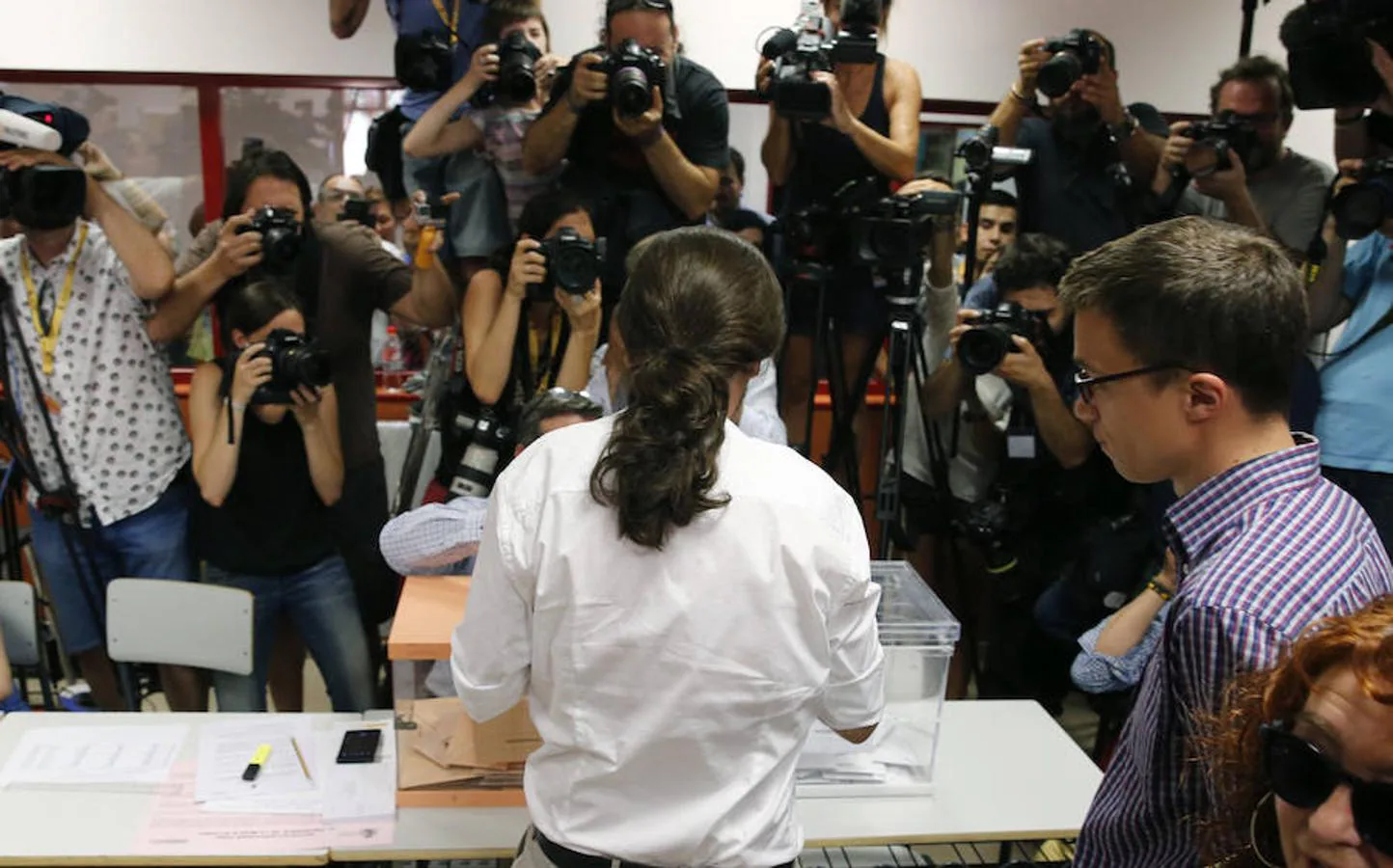 El candidato de Unidos Podemos a la presidencia del Gobierno, Pablo Iglesias (c), junto al jefe de campaña, Íñigo Errejón (d), vota en el instituto Tirso de Molina de Madrid