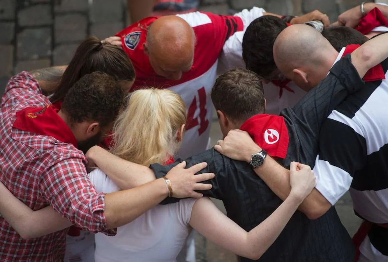 Un grupo de personas se abraza y rezan minutos antes de correr el quinto encierro de los sanfermines 2016 en Pamplona