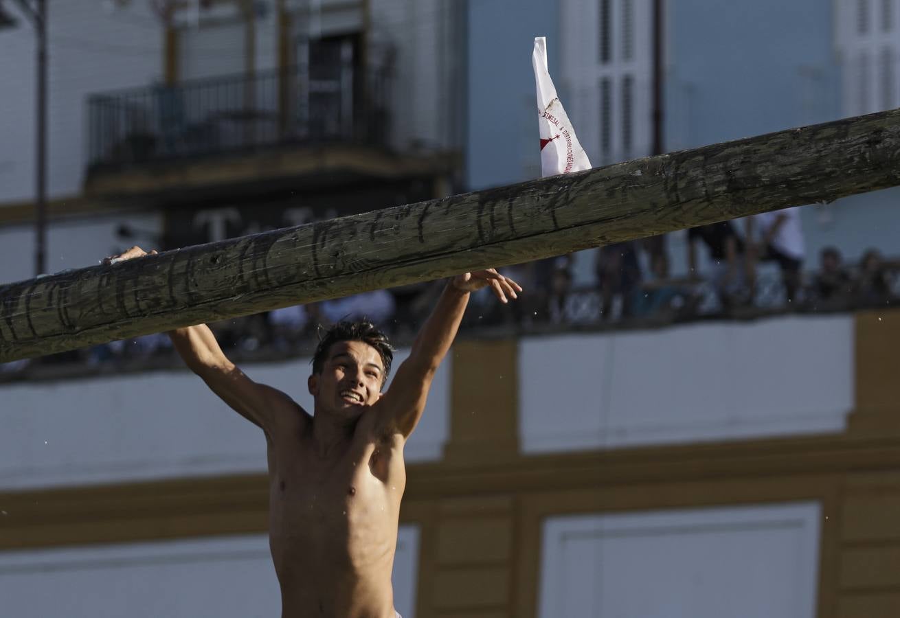 Los participantes deben caminar sobre el poste, previamente embadurnado con grasa resbaladiza, evitando caer al agua, hasta alcanzar el banderín del otro extremo