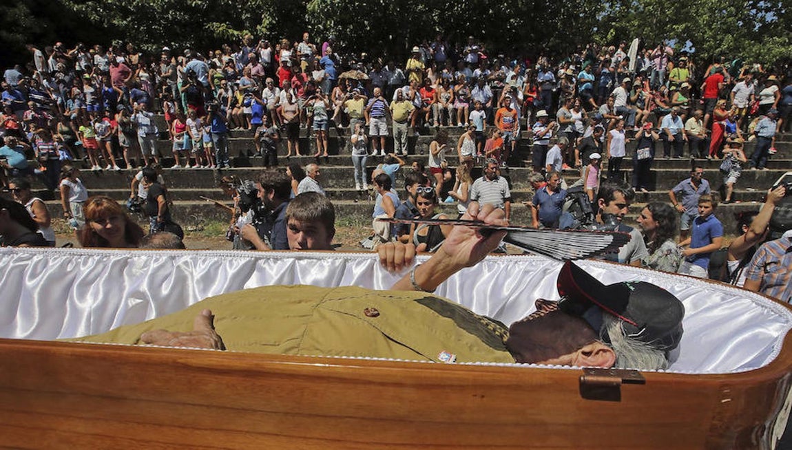 Un hombre mayor se protege del sol mientras es portado en un ataúd. 