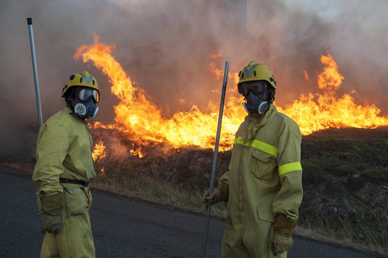 Dos personas participan en las labores contra el incendio forestal declarado en Avión (Ourense), en el que trabajan 3 agentes, 12 brigadas, 9 motobombas, 3 palas y 4 helicópteros para evitar que el fuego alcance el núcleo de Porreira. 