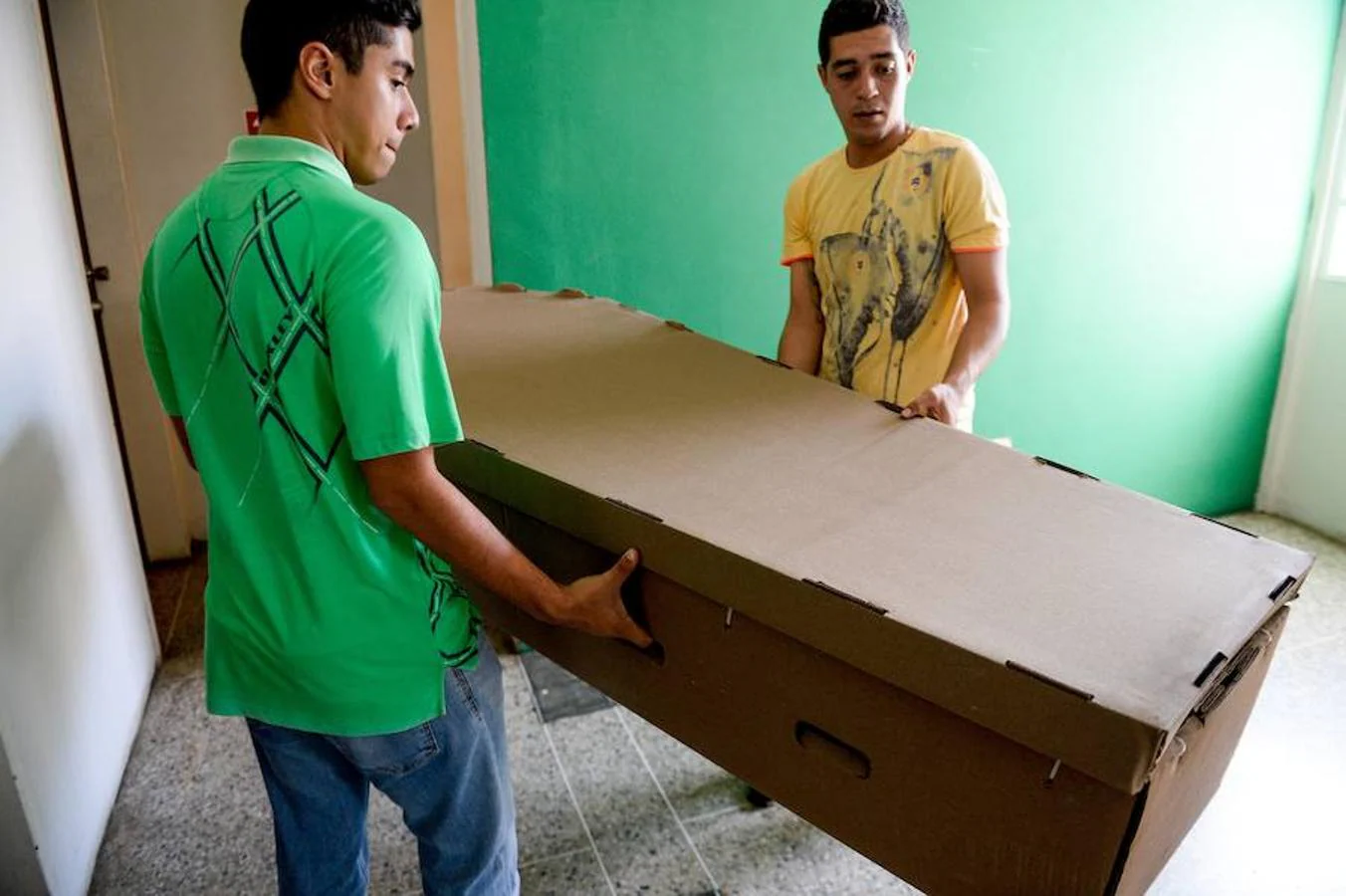 Dos muchachos cargan un ataúd de cartón en la ciudad de Barquisimeto.