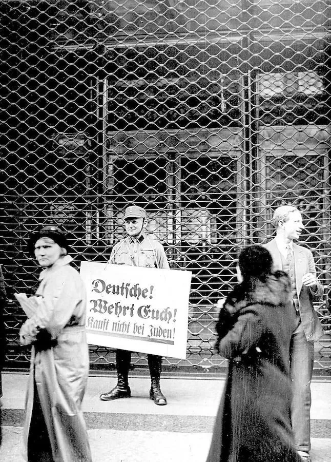Un simpatizante del partido nazi, frente a los almacenes Tietz de Berlín. En su pancarta, animaba a los transeúntes a no entrar en comercios judíos: «Defendéos, alemanes, y no compréis a los judíos».