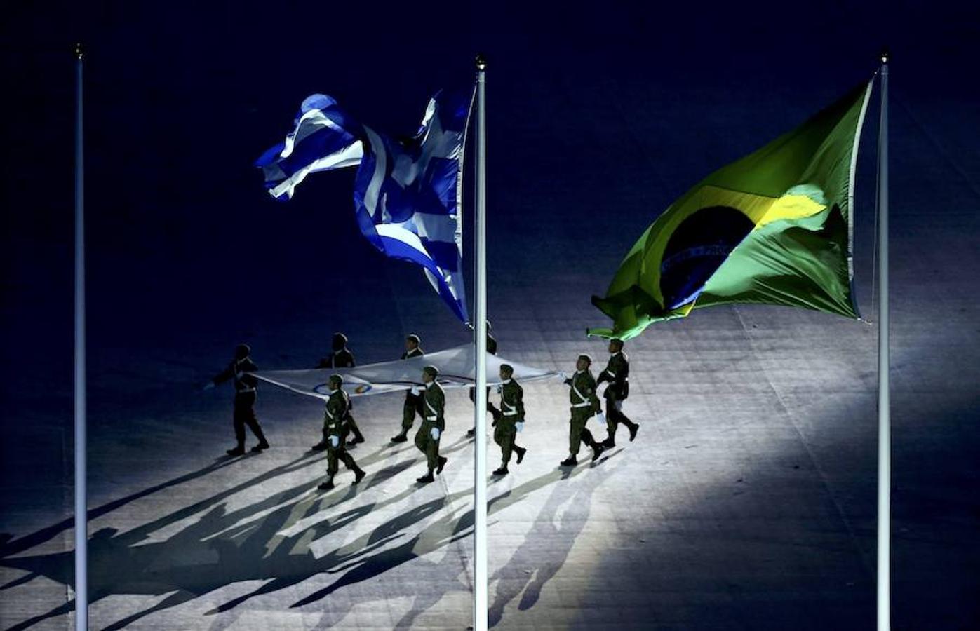 Izado de la bandera. Los militares portaron la bandera olímpica, flanqueada por las banderas nacionales de las delegaciones. En la foto, las banderas de Brasil, anfitrión, y Grecia, país originario de los Juegos, con la olímpica de fondo