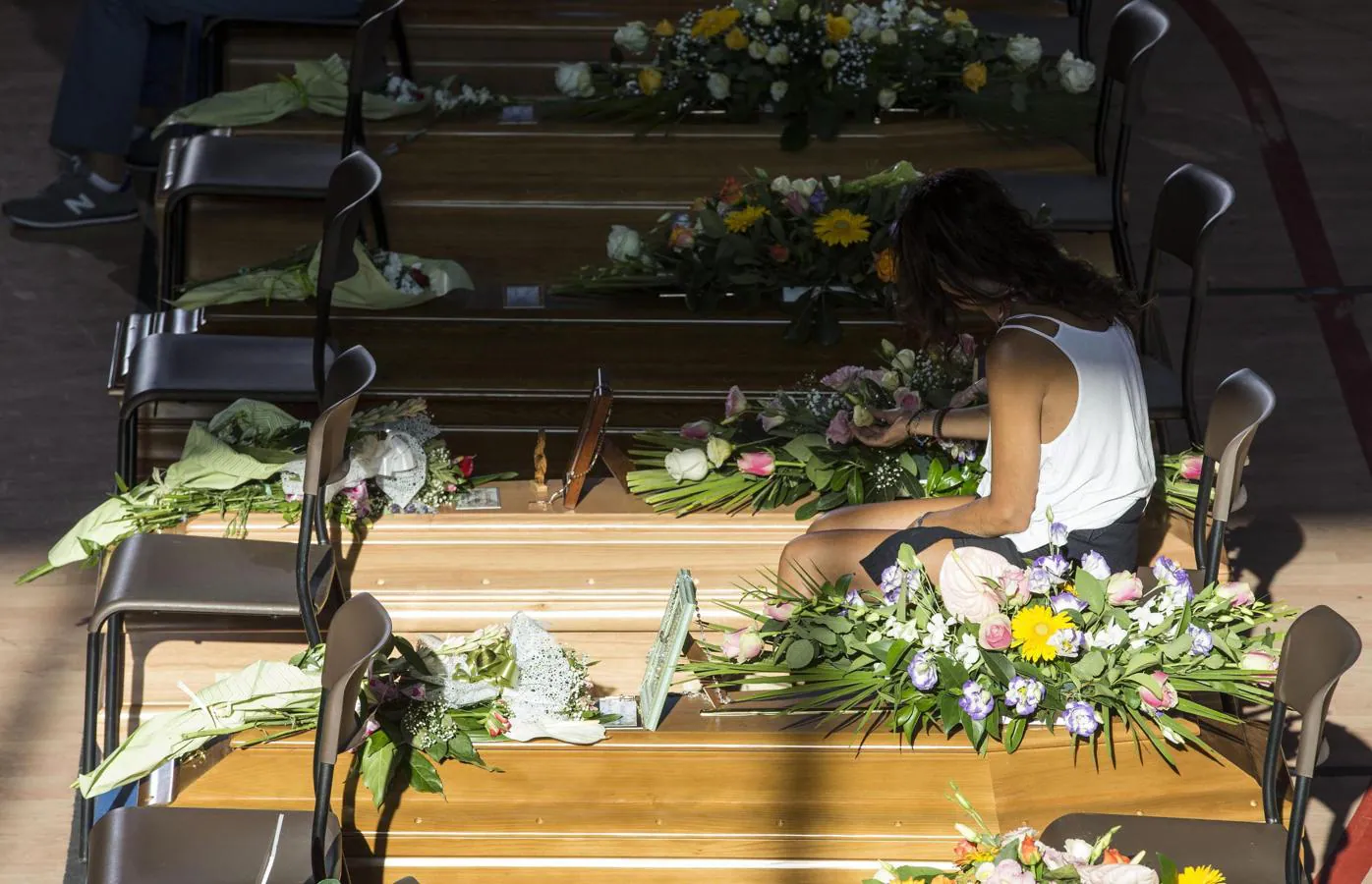 Una mujer acaricia una flor sobre el ataúd de uno de sus familiares antes del funeral celebrado en Ascoli Piceno. 