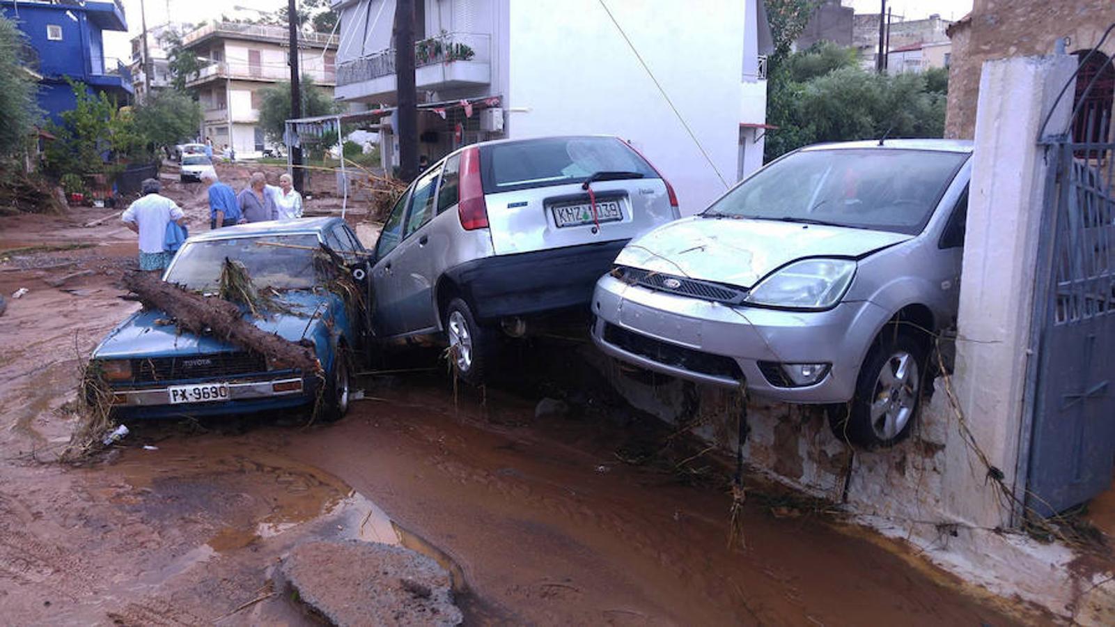 Vecinos se paran junto a los coches apilados como consecuencia de la tormenta en Kalamata.