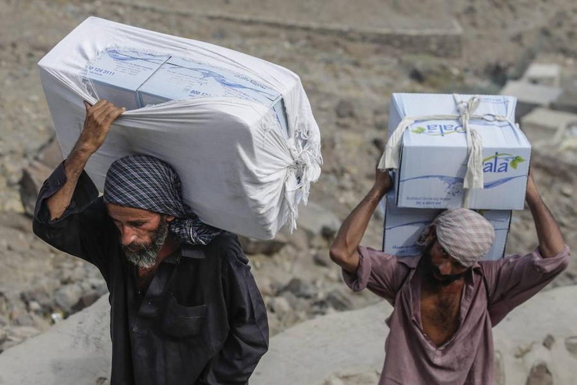 Unos trabajadores suben botellas de agua mineral al monte sagrado. 
