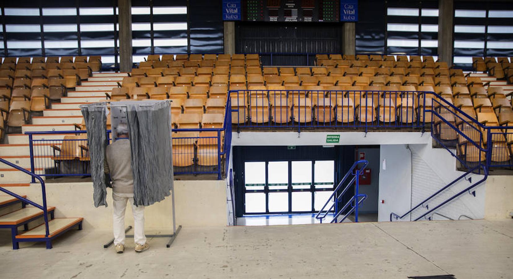 Un hombre elige la papeleta el colegio electoral habiltado en el polideportivo Mendizorrotza de Vitoria.