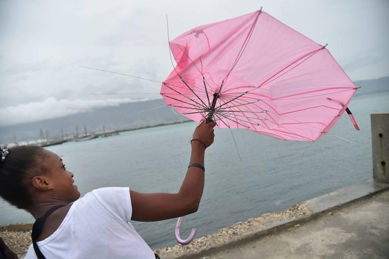 Una mujer lucha contra el viento y trata de reparar su paraguas en Cite Soleil, en la ciudad haitiana de Puerto Príncipe