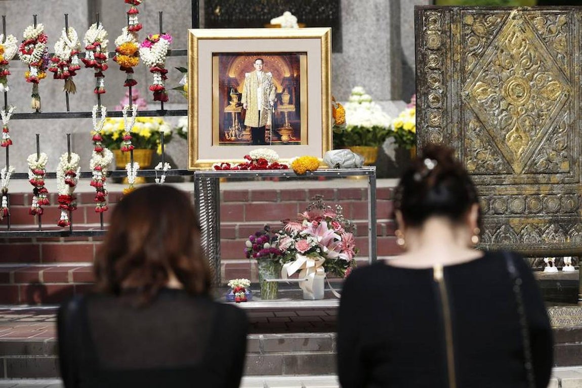 Tailandeses muestran su respeto mientras esperan el inicio del cortejo fúnebre del Rey Bhumibol Adulyadej. Efe