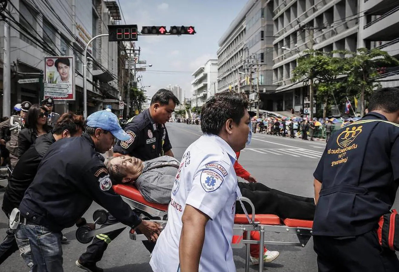 Paramédicos trasladan en camilla a una mujer que sufrió un desmayo mientras esperaba al traslado del Rey Bhumibol Adulyadej desde el hospital Siriraj en Bangkok