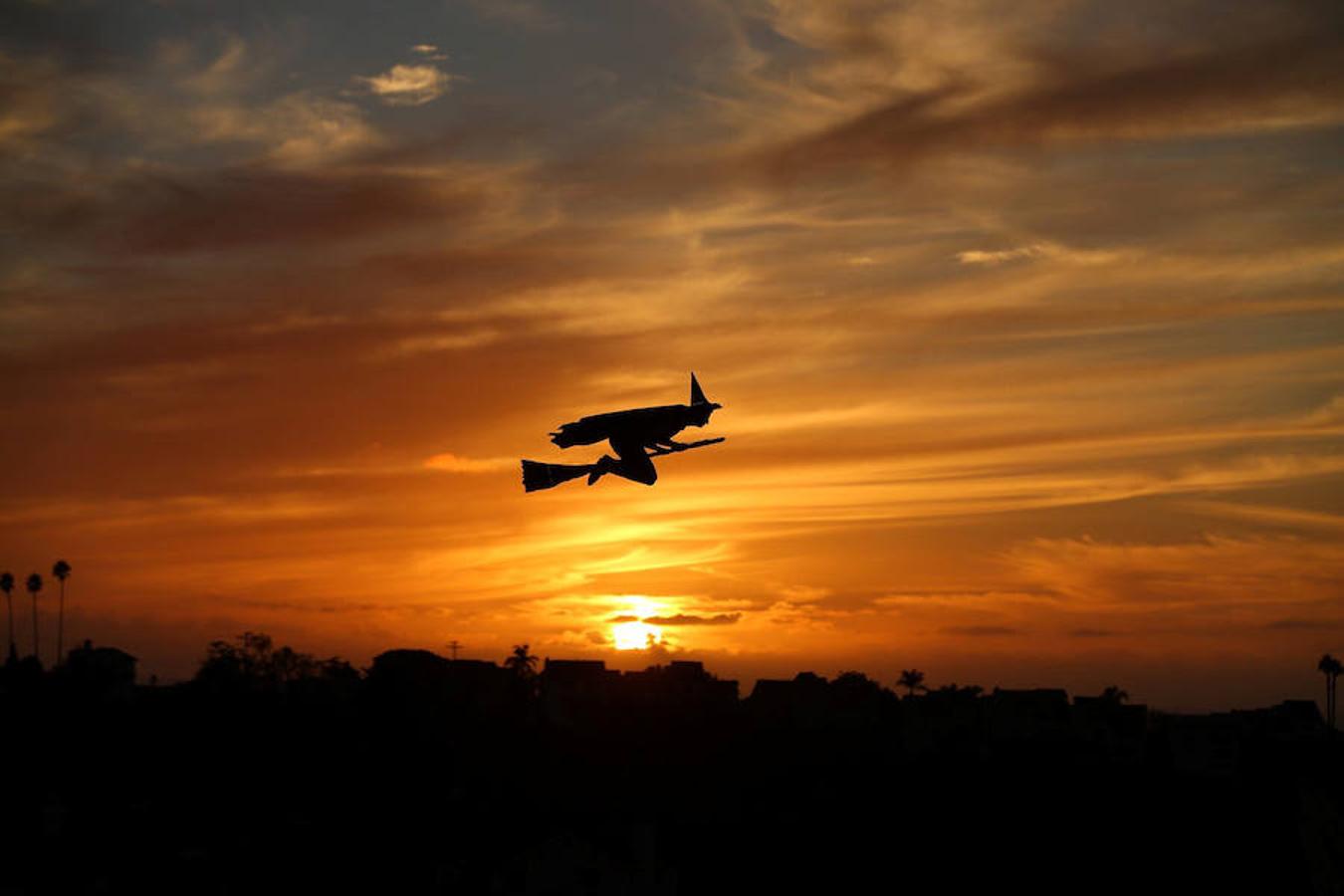 Un avión con forma de bruja subida en su escoba, manejado por control remoto, sobrevuela el vecindario de Encinitas (California)