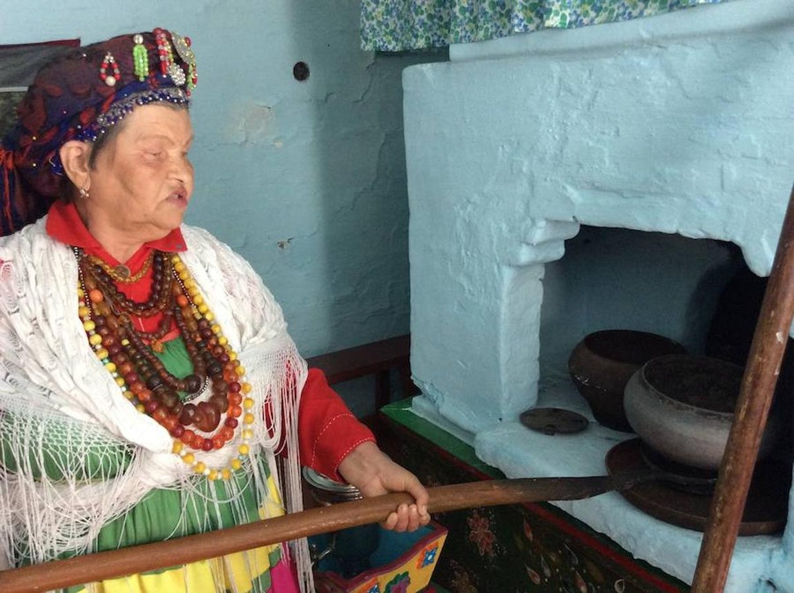 Una mujer introduce recipientes en el horno (encima está la cama) que caldea la habitación que se utiliza en invierno. Para el verano, se utiliza otra parte de la casa. 