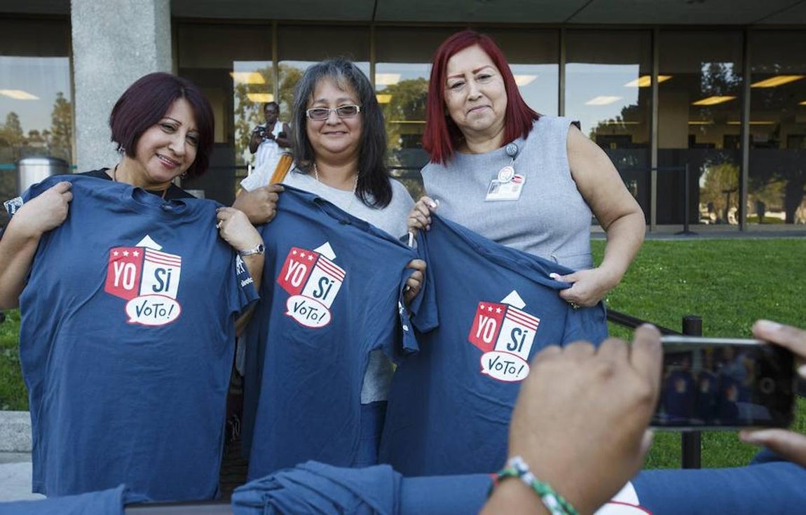 Unas mujeres latinas posan con una camiseta con la inscripción «Yo sí voto» tras emitir su voto durante la elecciones. Efe