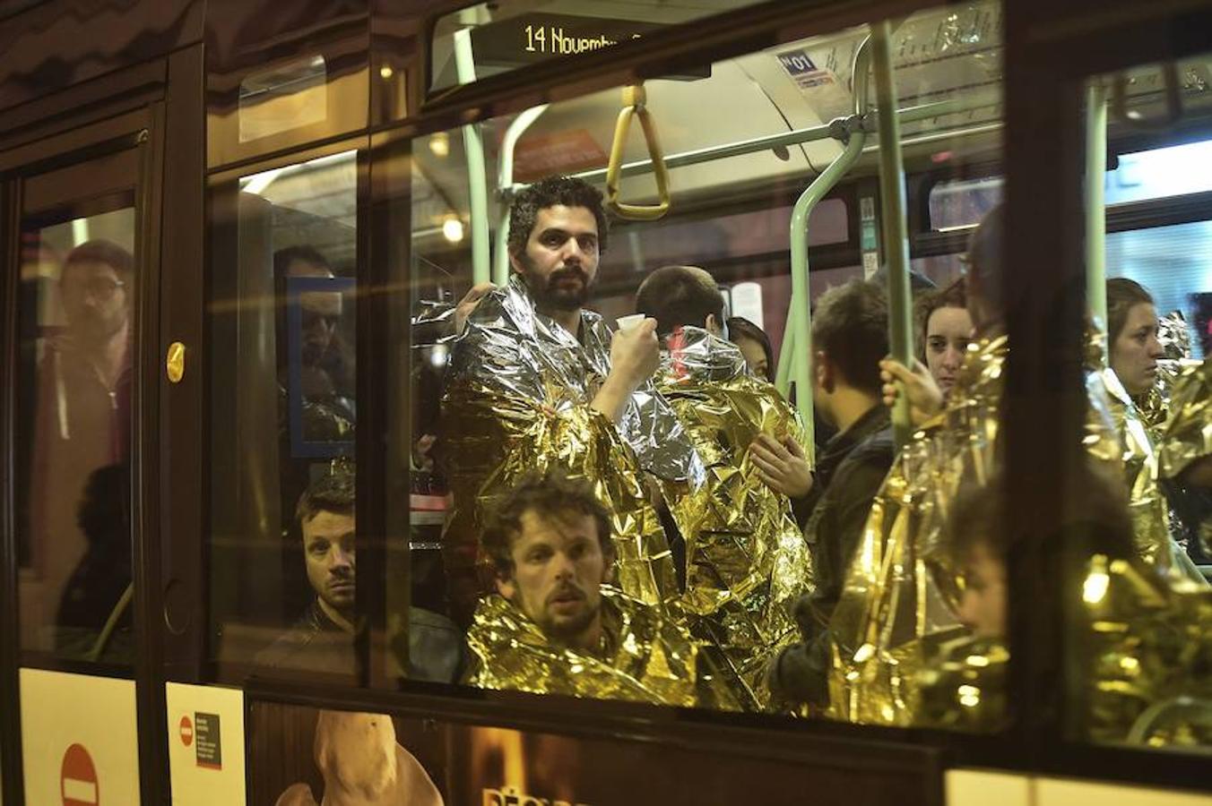 Varias personas cubiertas con mantas térmicas son evacuadas en un autobús en las inmediaciones de la sala Bataclan. 