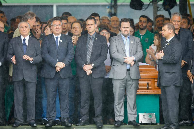 El presidente Michel Temer (i) y el entrenador de la selección brasileña Tite (d) son vistos junto a féretros de los jugadores y equipo técnico del club brasileño Chapecoense durante el velorio colectivo de las víctimas. 