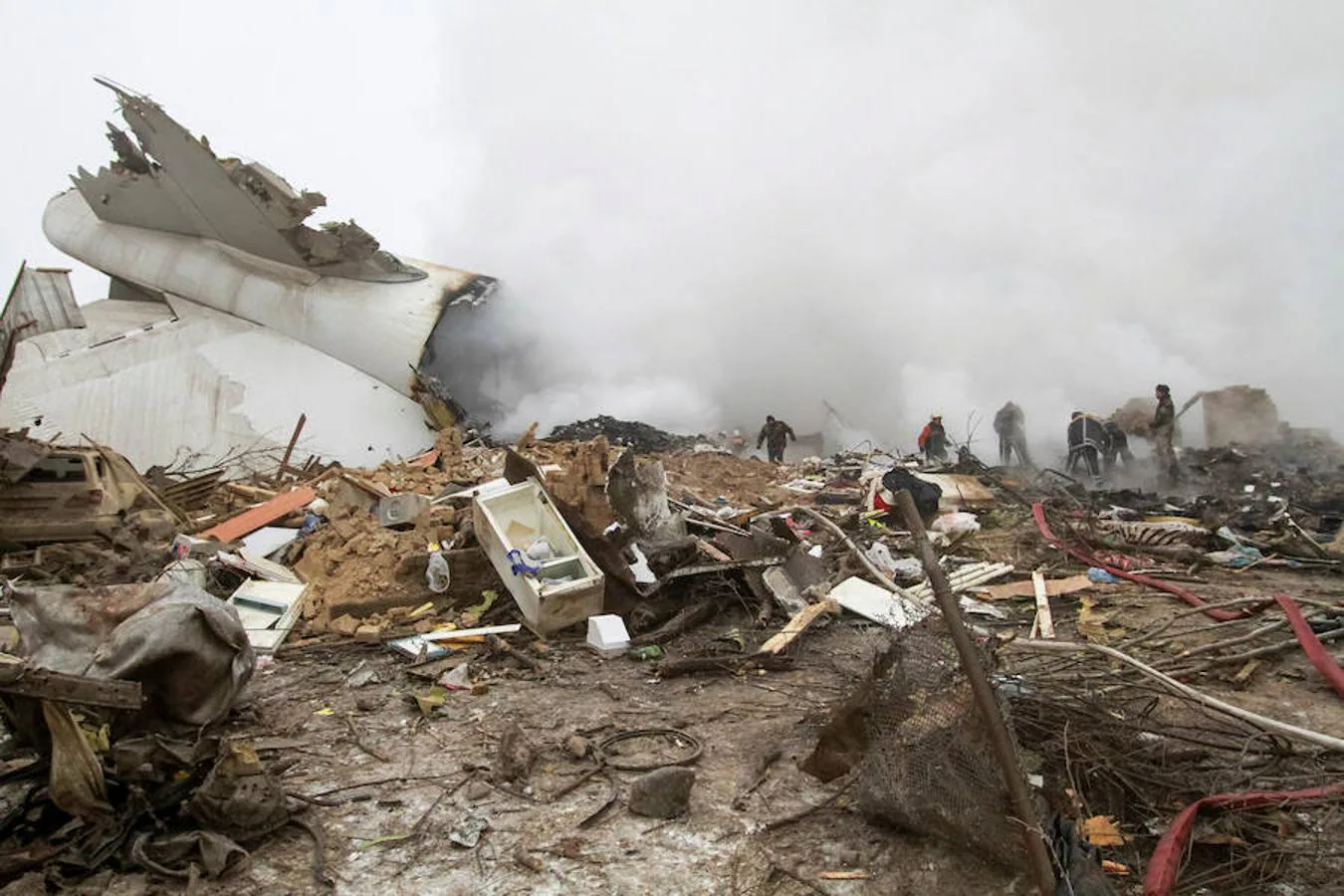 Restos del avión siniestrado entre los de las viviendas destruidas y la densa niebla.
