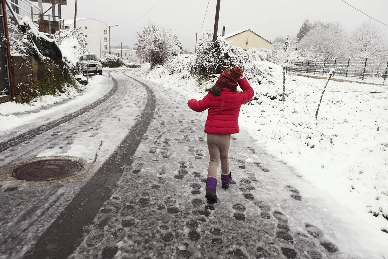 Una niña pasea sobre una carretera nevada en el municipio de Palas de Rei (Lugo)