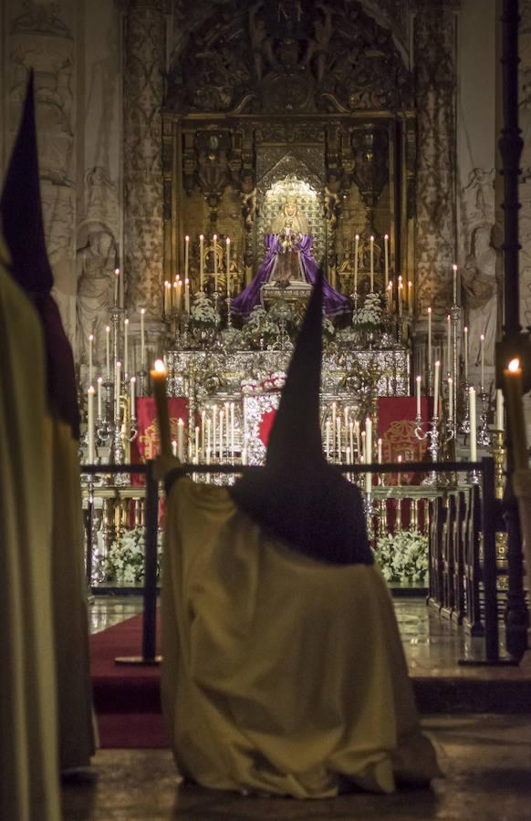Un nazareno pone velas en la catedral. 