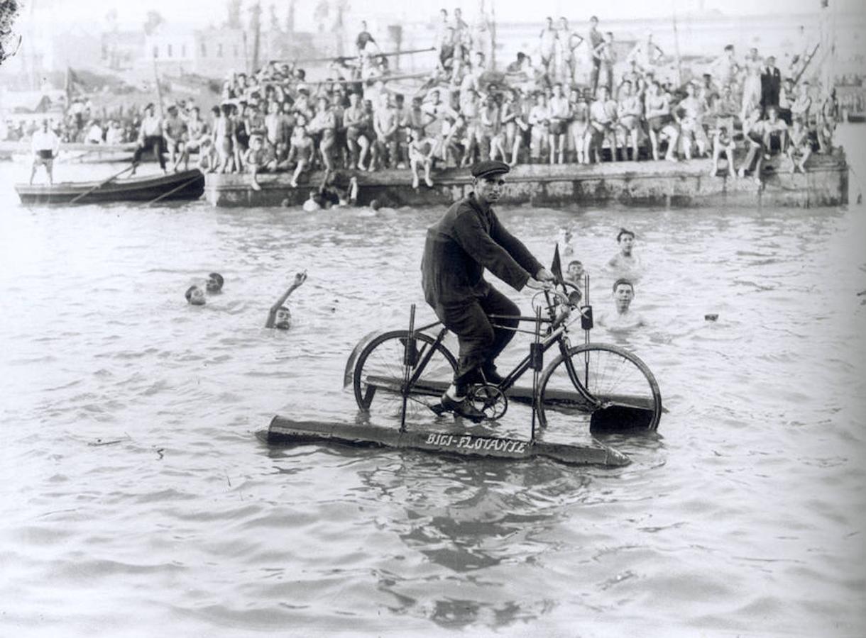 Manuel Pérez, inventor de la bici flotante, pasea por el río mientras se celebra la cucaña en Sevilla en 1927. 