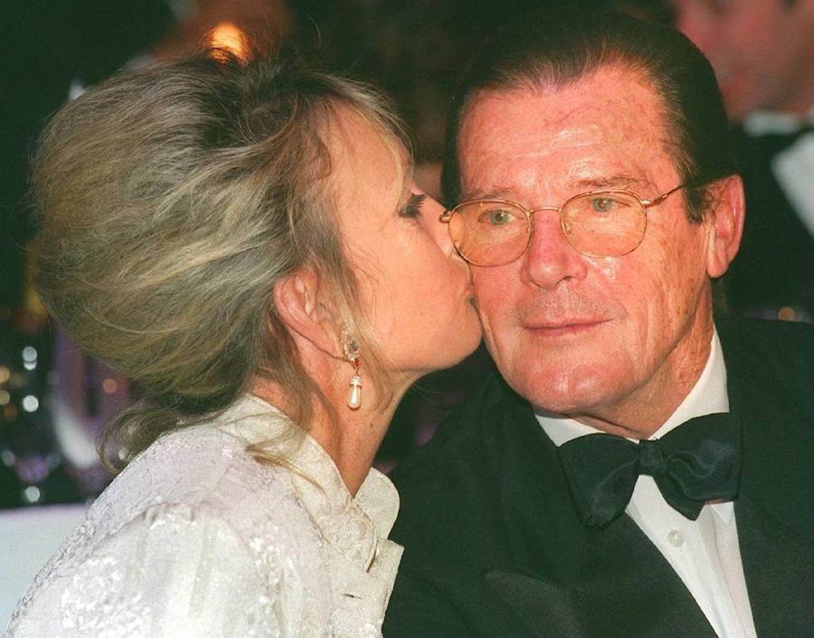 Cuatro matrimonios. Roger Moore recibe un beso de su novia Christina Tornstrup en una gala para recaudar fondos para WWF en 1999, tiempo después se convertiría en su cuarta mujer.