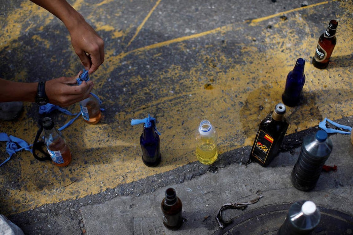 Manifestantes rellenan botes con derivados del petróleo antes de las protestas. Reuters
