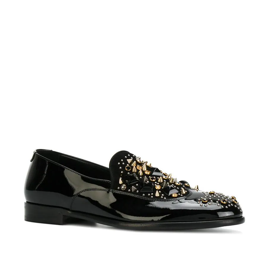 Zapatos slippers en charol negros con detalles en dorado (995 €).