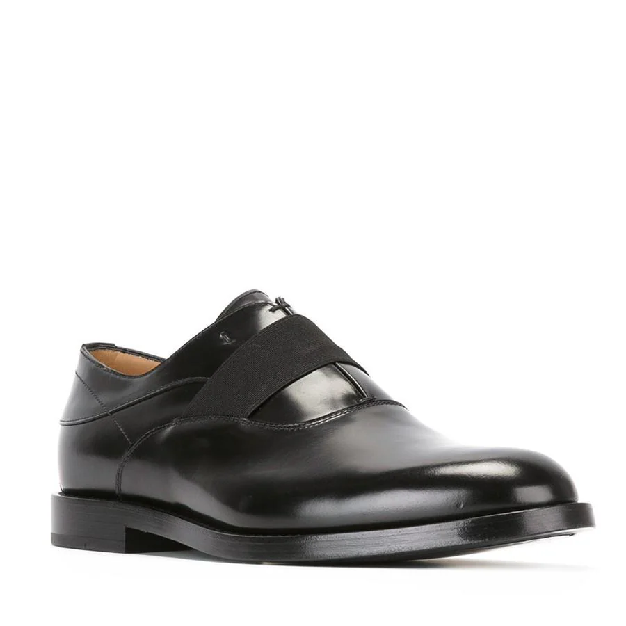 Zapatos estilo oxford en piel negros con cordones interiores , goma elástica al frente y suela de cuero (750€).