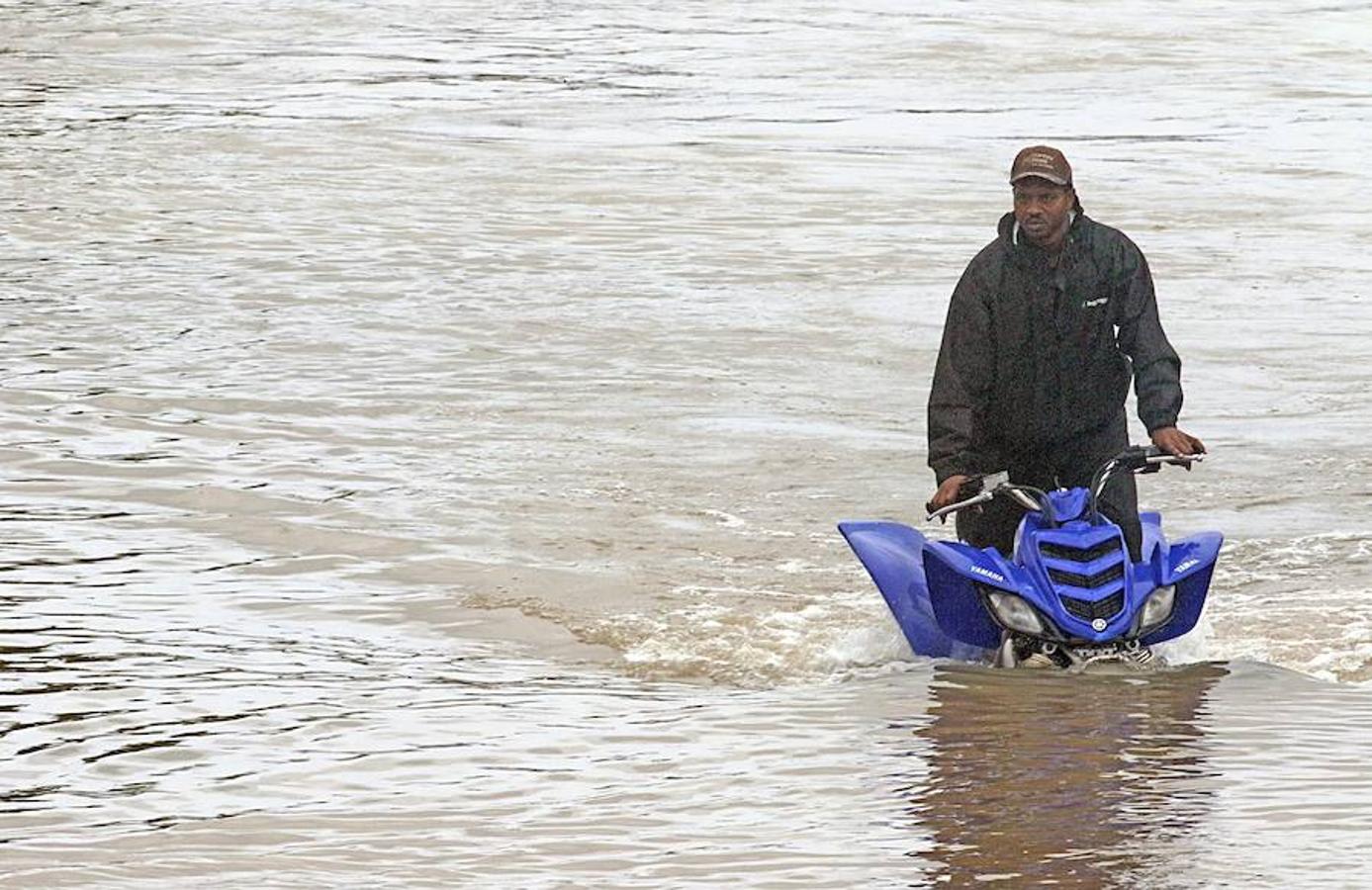 Un hombre conduce su vehículo a pesar de las inundaciones. 