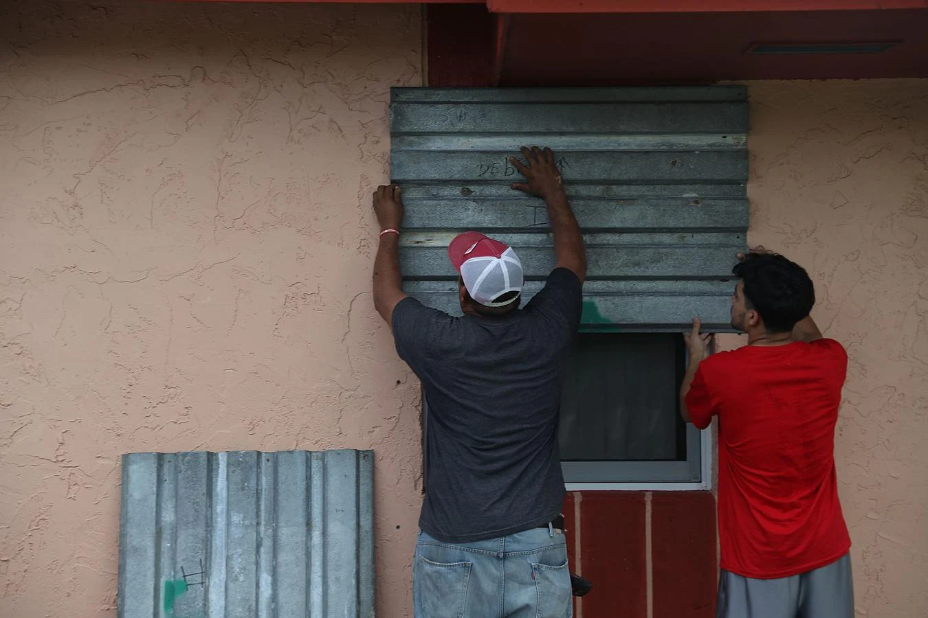 Dos hombres tapan las ventanas de una casa ante la inminente llegada del huracán Irma a Florida. 