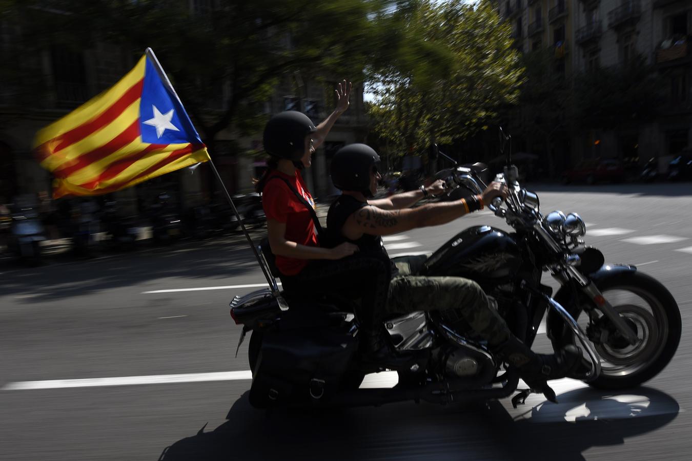Dos jóvenes llevan una bandera estelada en su moto durante la Diada de 2014. 